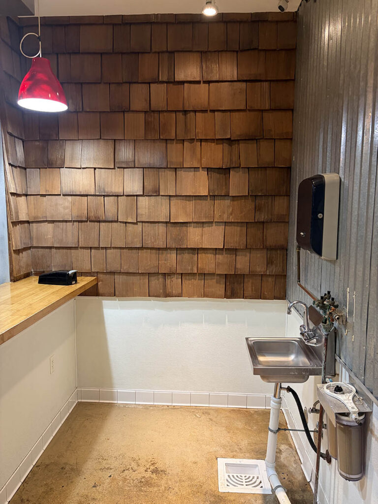 Clean commercial service area with hand sink and cedar shingle wall