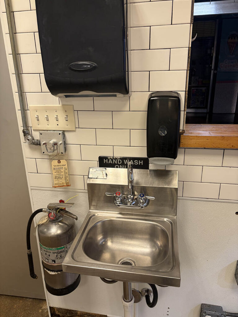 Commercial hand-wash sink with soap and towel dispensers after cleaning