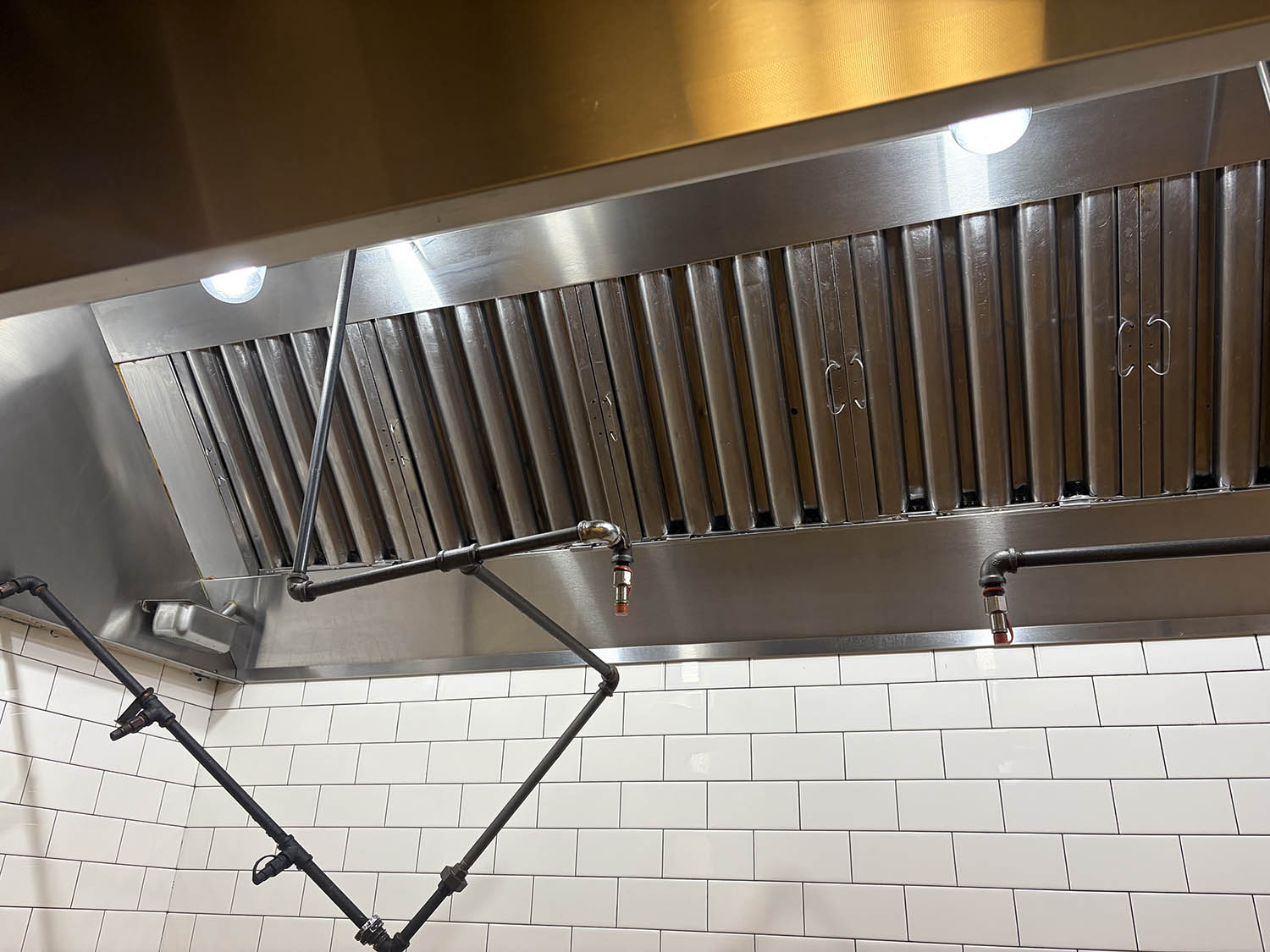 Stainless exhaust hood over a subway tile wall after a commercial kitchen clean
