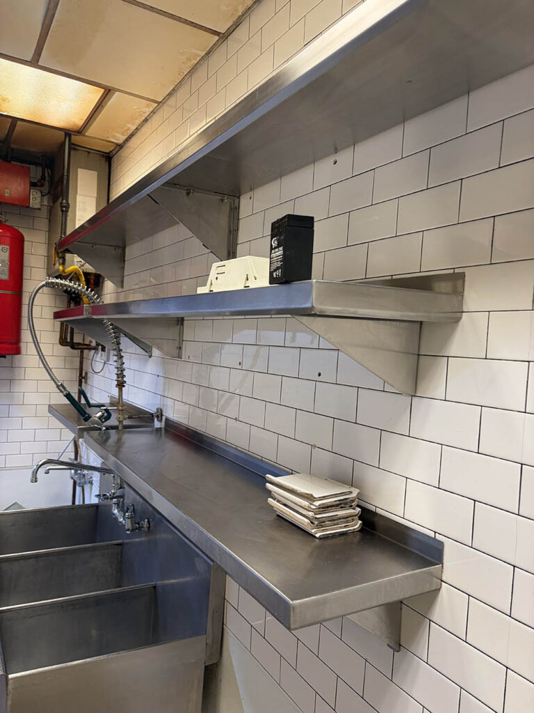 Commercial kitchen prep sinks and stainless shelving after a deep clean