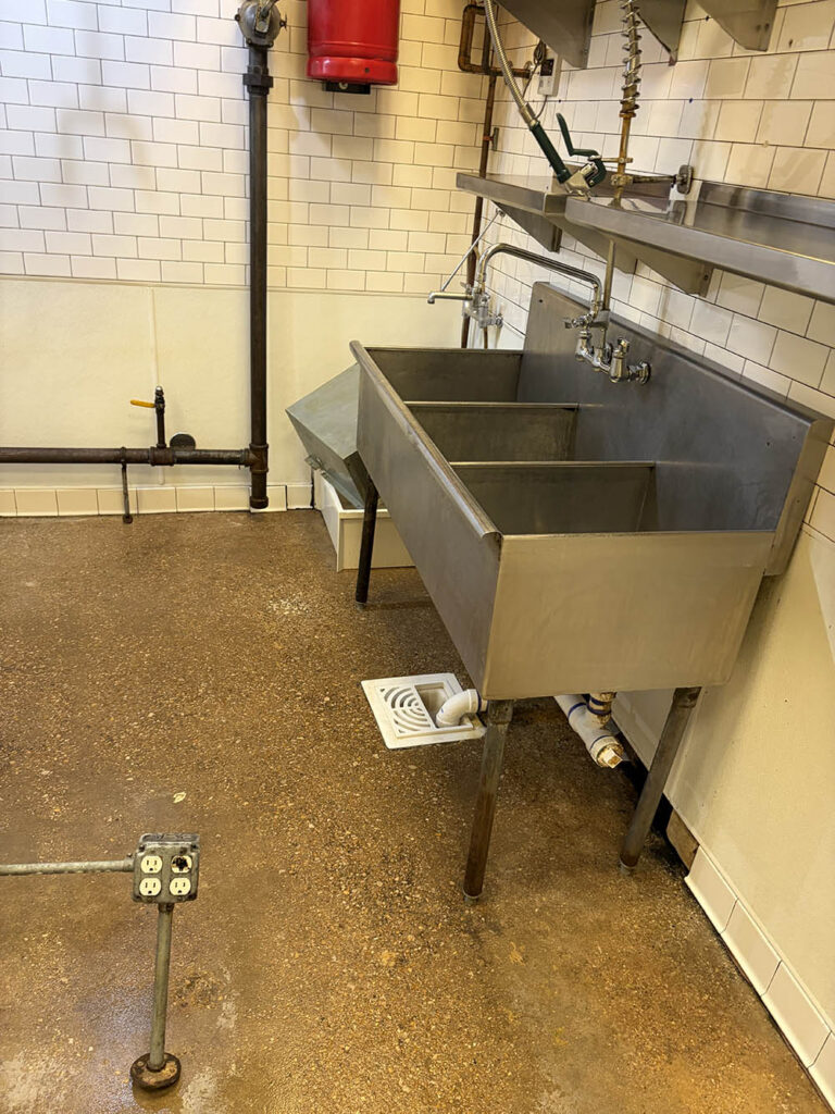 Three-compartment stainless sink in a commercial kitchen after cleaning