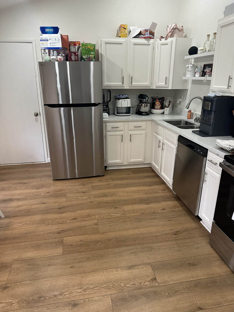Galley kitchen with white cabinets and stainless appliances after a cleaning