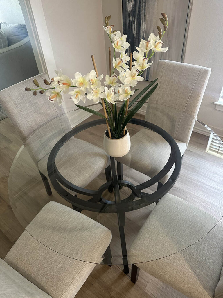 Glass dining table with an orchid centerpiece after a party cleaning
