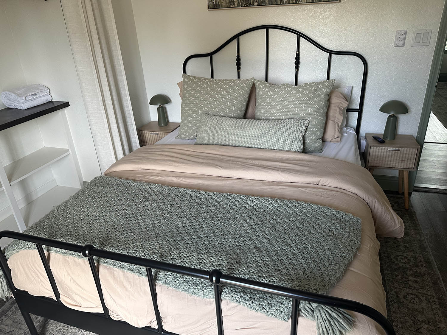 Guest bedroom with an iron bed frame and made bed after a house cleaning