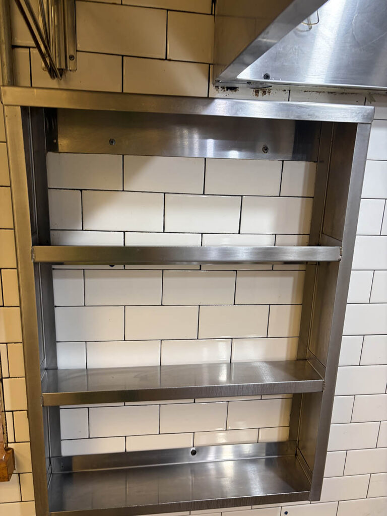 Stainless shelving unit on a subway tile wall after commercial cleaning