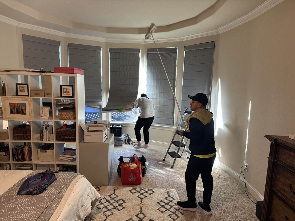 Open Hands Cleaning Services crew cleaning window shades in a DFW bedroom