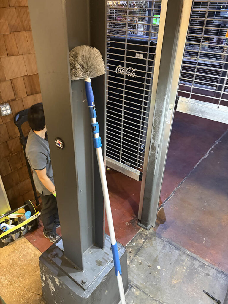 Open Hands crew dusting high surfaces in a commercial space