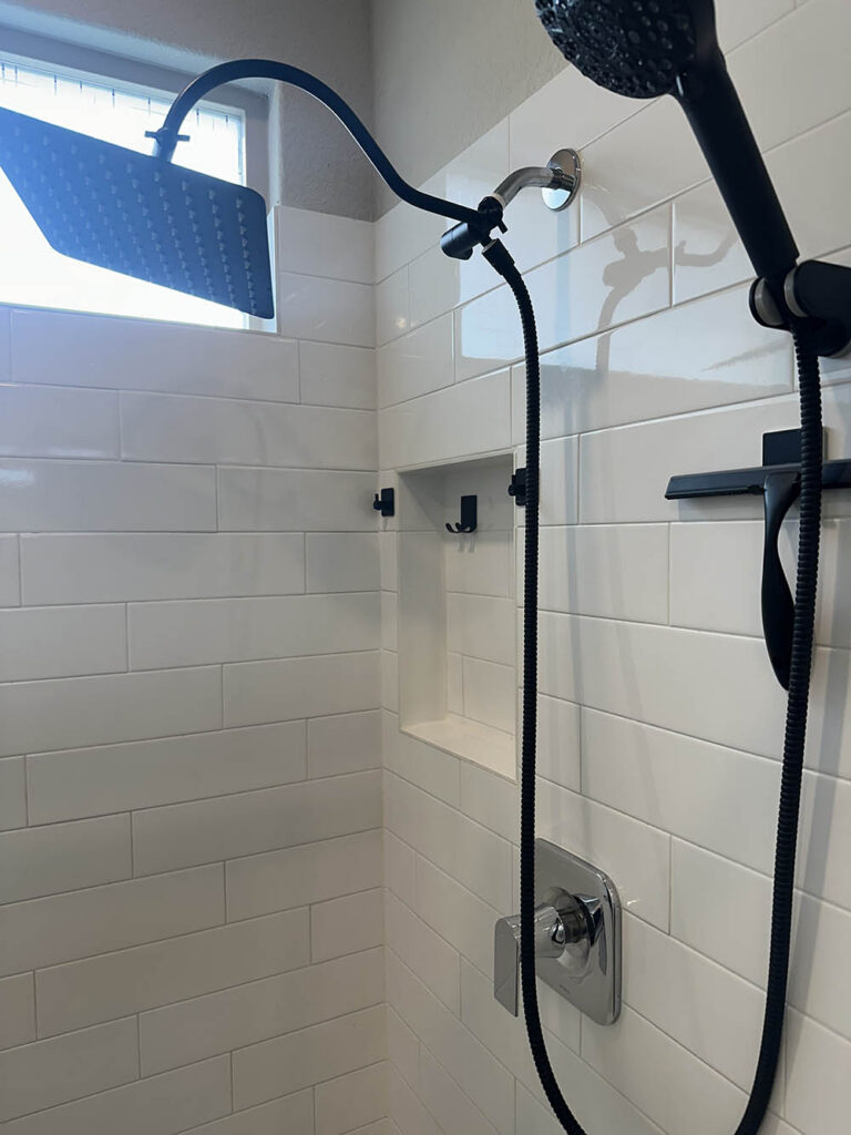 New subway tile shower with black fixtures after post-construction cleaning