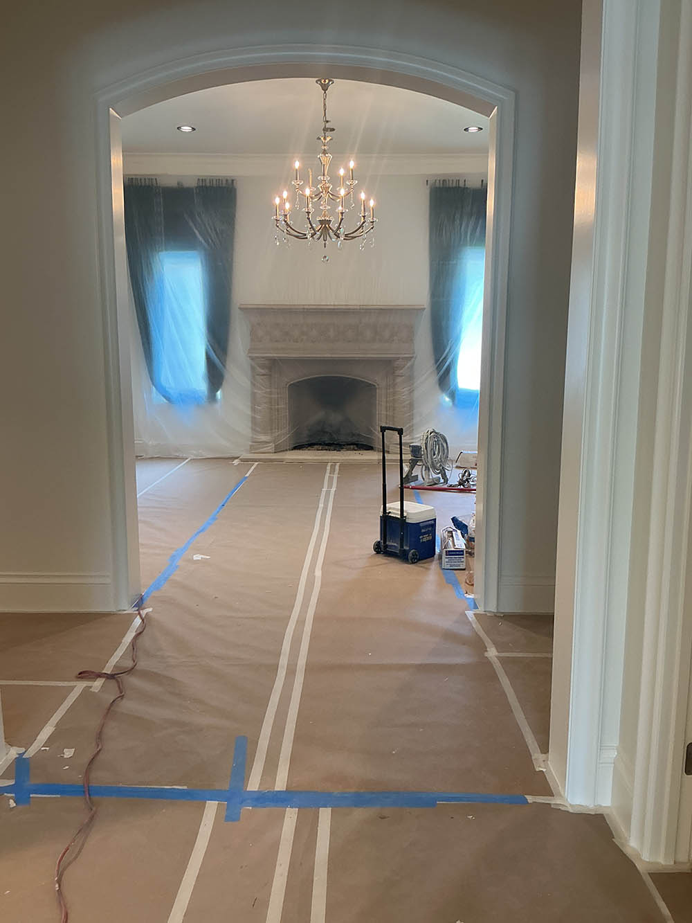 Formal living room with chandelier and floor protection during post-construction cleanup